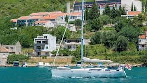 Un'imbarcazione a vela ormeggiata vicino a una cittadina costiera, con edifici sullo sfondo.