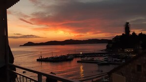 A sunset view from a balcony overlooking a marina with boats and a distant island.