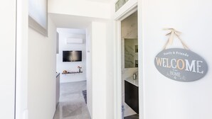 Un couloir moderne avec un téléviseur à écran plat fixé au mur, un panneau d’accueil et un comptoir surmonté d’une plaque de marbre.