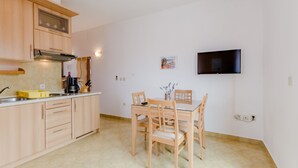 Eine moderne Küche mit Holzschränken, einem Esstisch mit Stühlen und einem an der Wand befestigten Flachbildfernseher.