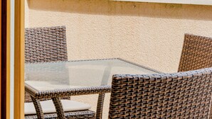Ein Balkon mit Korbstühlen und einem Tisch, der auf ein Gewässer blickt.
