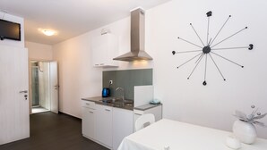 A modern kitchen with white cabinetry, a stainless steel range hood, a built-in oven, and a wall-mounted clock. - Magdales - Two Bedroom Apartment with Balcony (Omis)