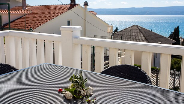 A balcony with a table and chairs, overlooking a body of water and buildings. - Magdales - Two Bedroom Apartment with Balcony (Omis)