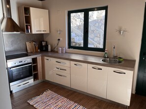 Une cuisine moderne dotée d’un four encastré, d’une grande fenêtre et d’un évier.