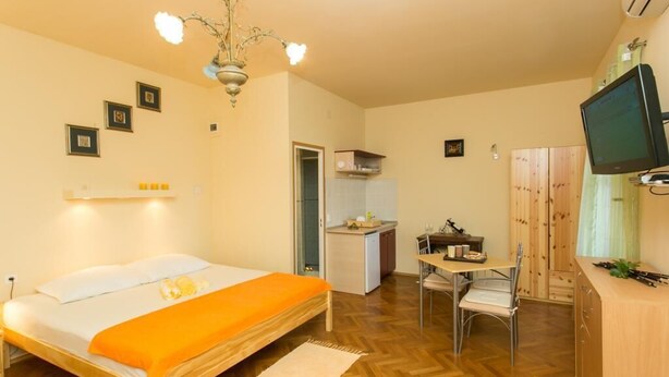 A bedroom with a bed, a desk, a chair, a television, and a kitchenette. - Villa Iveta- Triple Room (Ground Floor) - Martina (Dubrovnik)