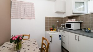Une cuisine compacte équipée d’un réfrigérateur, d’un four à micro-ondes et d’une petite table à manger avec des chaises.