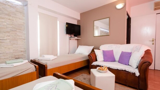 Une pièce confortable avec un lit, un canapé, une télévision et un miroir.