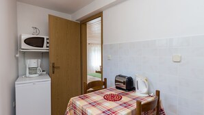 A compact kitchen with a microwave, coffee maker, toaster, and a table with a plaid tablecloth. - Apartments Miskovic - Studio Apartment with Balcony and Sea View (East) (Kolocep)