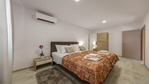 Een slaapkamer met een bed, nachtkastje, lamp en een airconditioning.