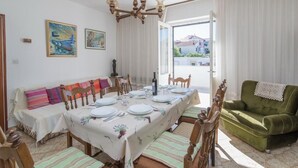 A dining area with a table set for four, a sofa, and a green armchair. - Apartment M&P - Four Bedroom Apartment with Terrace Sea View (Supetar)