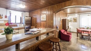A kitchen with wooden paneling, a stainless steel refrigerator, a dining table with chairs, and a red armchair. - Holiday home Villa Spilla - Three Bedroom Home with Terrace (Selca)