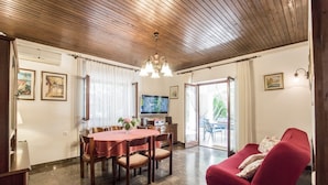A dining area with a wooden ceiling, a TV, and a red sofa. - Holiday home Villa Spilla - Three Bedroom Home with Terrace (Selca)