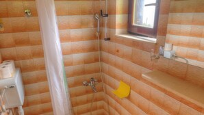 Kylpyhuone, jossa on suihku, wc, pesuallas ja pieni ikkuna.