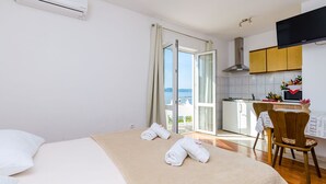 Une chambre d’hôtel comprenant un lit, une chaise, une table, un coin cuisine et un balcon avec vue.