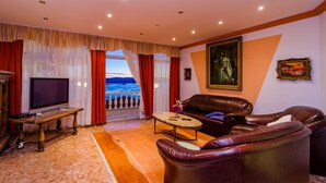 Una sala de estar con un sofá, una mesa de centro, un televisor y vista al mar a través de una ventana.