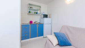 Cozinha compacta com armários azuis, geladeira branca e micro-ondas.