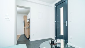 Una sala moderna con una mesa de centro de vidrio, un sofá y una puerta oscura.
