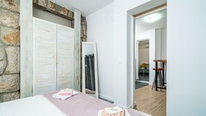 Una habitación con cama, mesa de masaje, espejo y pared de piedra.