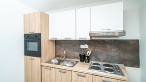 Una cocina compacta con horno integrado, un lavamanos de acero inoxidable y una estufa a gas.