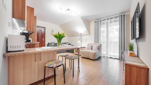 Una cocina moderna con armarios de madera, microondas integrado y comedor con mesa y taburetes coloridos.