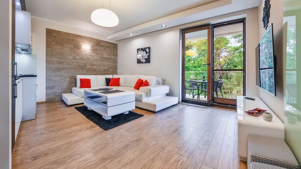 Una sala de estar moderna con un sofá blanco, una mesa de centro y un ventanal con vista a la vegetación.