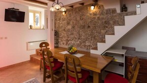 Ein Essbereich mit Holztisch, rot gepolsterten Stühlen, einer Steinwand und einer Treppe.