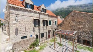 Ein Gebäude aus Stein mit rotem Ziegeldach, einem kleinen Balkon und einem Kieshof.
