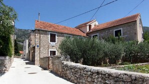 A narrow stone-paved street flanked by traditional stone buildings with red-tiled roofs.