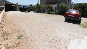 A gravel driveway leading to a house with a red car parked in front.