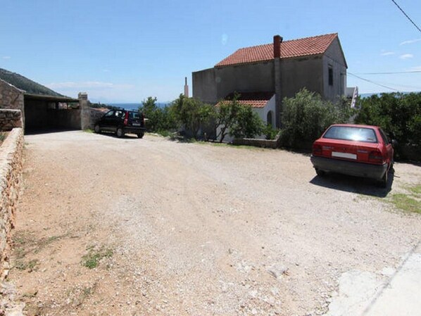A gravel driveway leading to a house with a red car parked in front. - Apartments Nadia - Studio Apartment With Terrace  (A1) (Bol)
