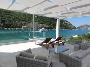 Relax in a serene outdoor seating area overlooking a picturesque bay with a clear sea view.