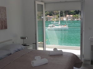 Relax in a spacious room with a large bed, nightstand, and sliding glass door leading to a marina view.