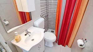 Un baño con lavamanos, inodoro y cortina de ducha blancos.