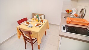Un pequeño comedor con una mesa preparada para dos, un microondas y un lavamanos.