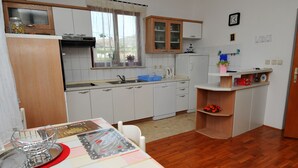 Une cuisine de taille réduite avec des meubles blancs, un plan de travail en bois et une fenêtre agrémentée de rideaux.