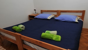 Un lit bien fait, avec une literie bleue, deux oreillers et des serviettes vertes.