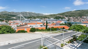 A coastal town with a prominent bridge, residential buildings, and a large cruise ship docked. - Guest House Bridge View - Double Room with Balcony and Sea View (Dubrovnik)