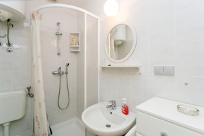 Ein Badezimmer mit Dusche, Waschbecken, Spiegel und Toilette.