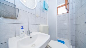 Een badkamer met een wit wastafel, toilet en douche.