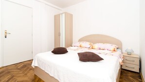 Een slaapkamer met een bed, nachtkastje, kledingkast en een deur.