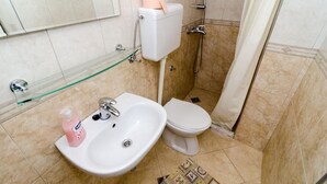 Een badkamer met een witte wastafel, toilet en douche.