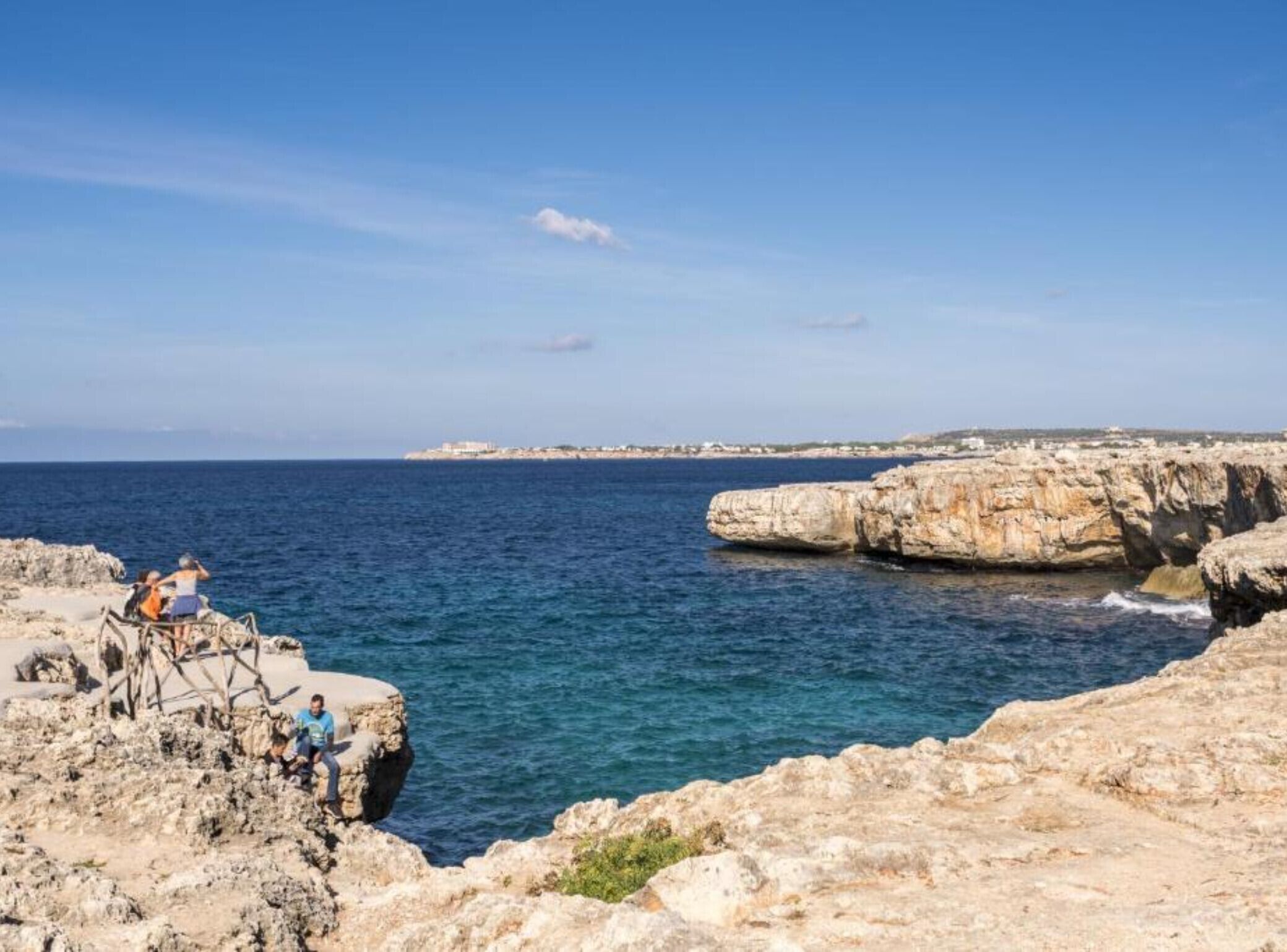 A coastal view with rocky terrain and a clear sky.