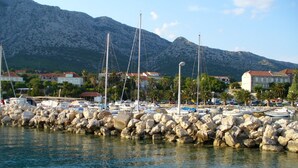 Un port de plaisance avec des bateaux amarrés, une digue rocheuse et des bâtiments en arrière-plan.