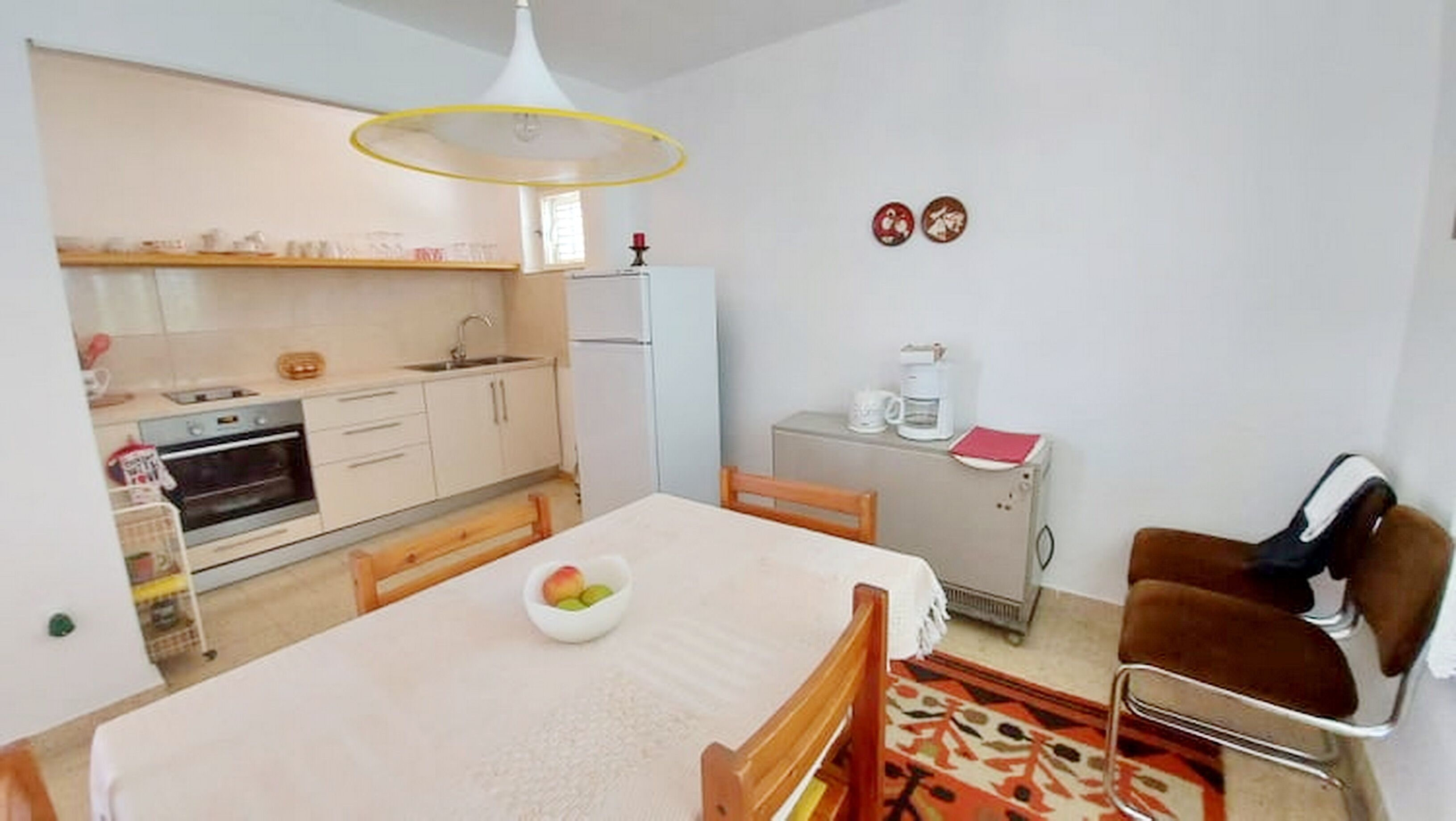 A compact kitchen with a dining area, a refrigerator, and a coffee maker.