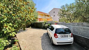 Une voiture blanche est garée dans une allée, avec un bâtiment en arrière-plan.