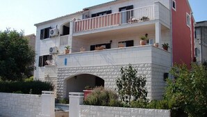 Ein zweistöckiges Gebäude mit Balkon, Blumentöpfen und einem steinernen Bogen.