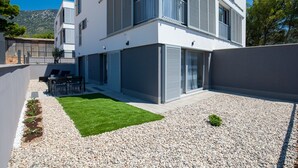 A modern two-story building with a flat roof, large windows, and a balcony. - Dva Galeba - One Bedroom Apartment with Garden Terrace (202) (Bol)