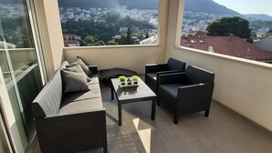 Un balcon avec un canapé, deux fauteuils et une petite table agrémentée de plantes.