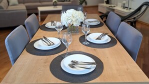 Un coin repas avec une table en bois dressée pour six personnes, entourée de chaises bleues.