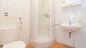 Un bagno con il water, uno spazio doccia e un lavandino.